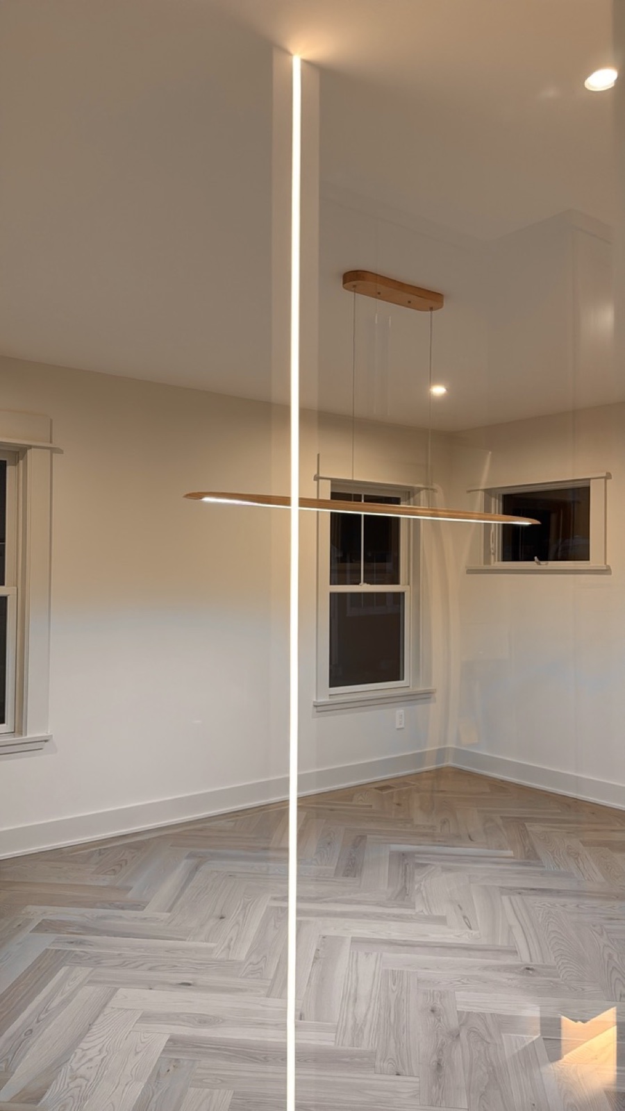 Modern dining room with linear wood pendant fixture and herringbone floor